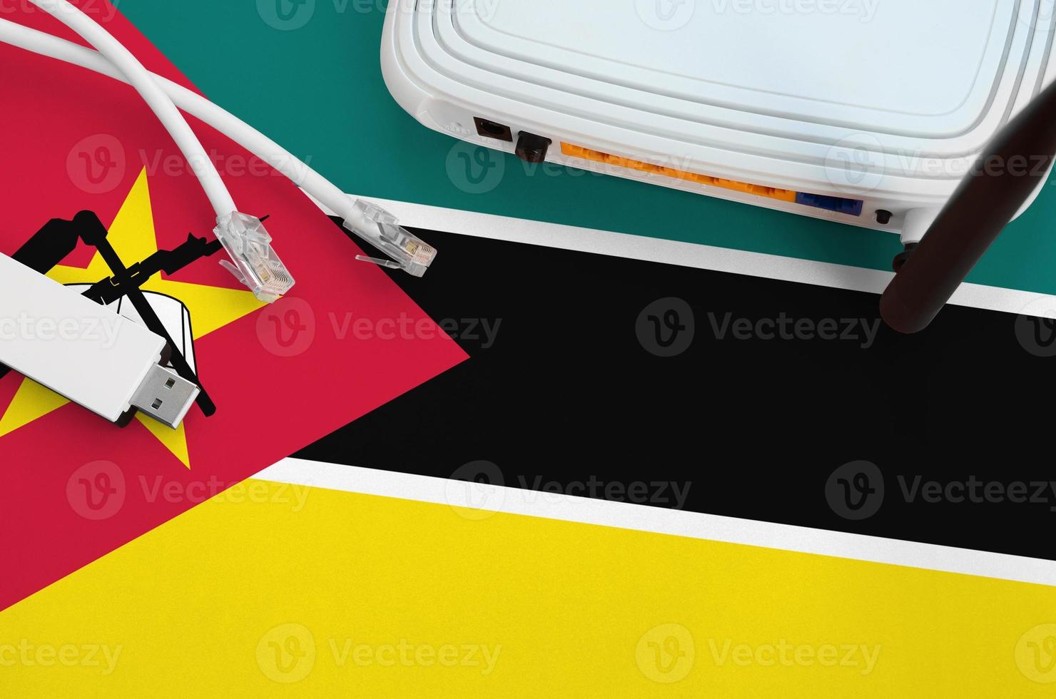 Mozambique flag depicted on table with internet rj45 cable, wireless usb wifi adapter and router. Internet connection concept photo