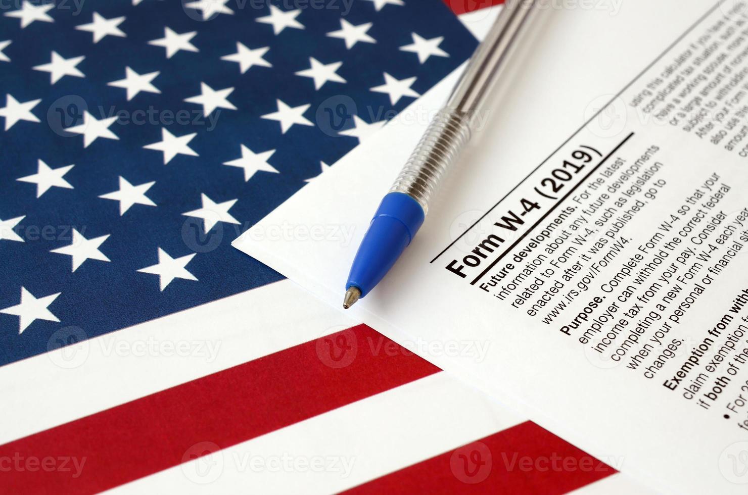 formulario w-4 instrucciones del certificado de asignación de retención del empleado y bolígrafo azul en la bandera de los estados unidos. formulario de impuestos del servicio de impuestos internos foto