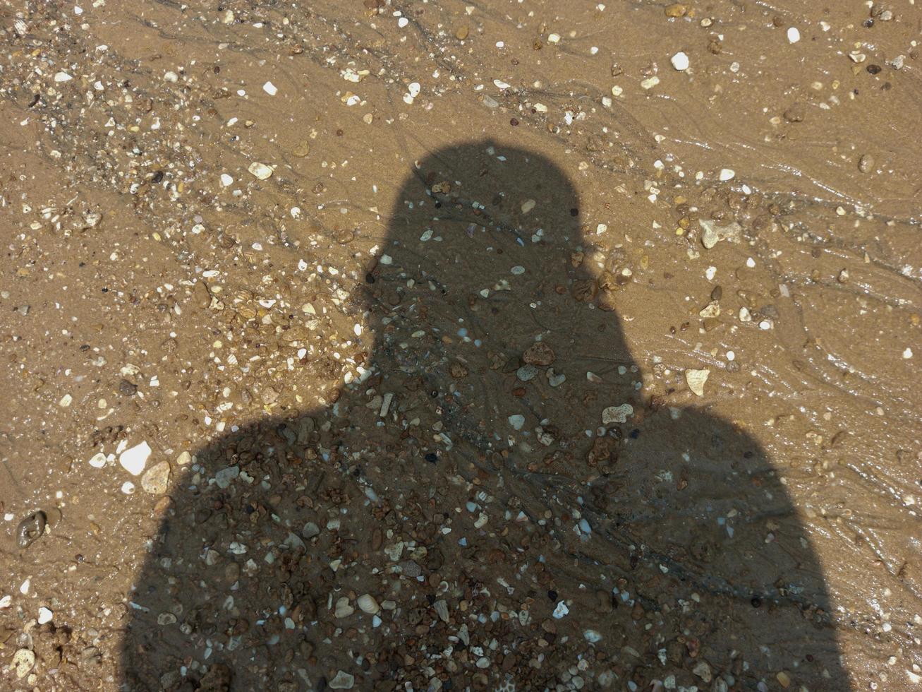 the shadow of an adult man on the beach sand photo