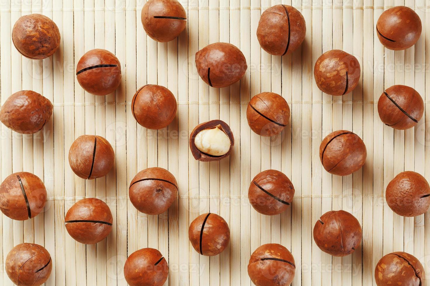 Flat composition with Australian macadamia nuts on bamboo light background. Patterns, repetitions photo