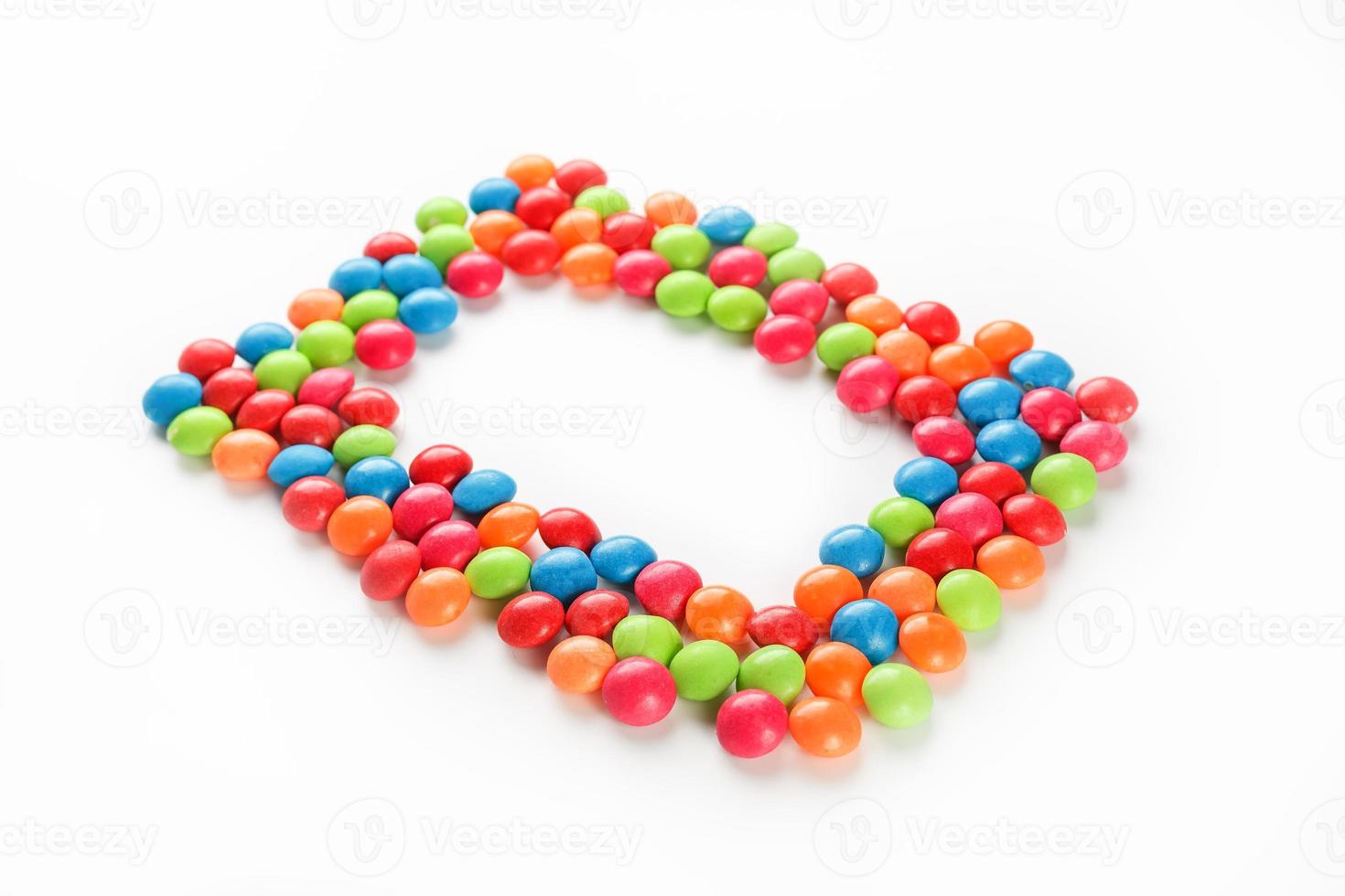Frame of multi-colored candies close up. Rainbow colored dragee multicolored glaze on a white background photo