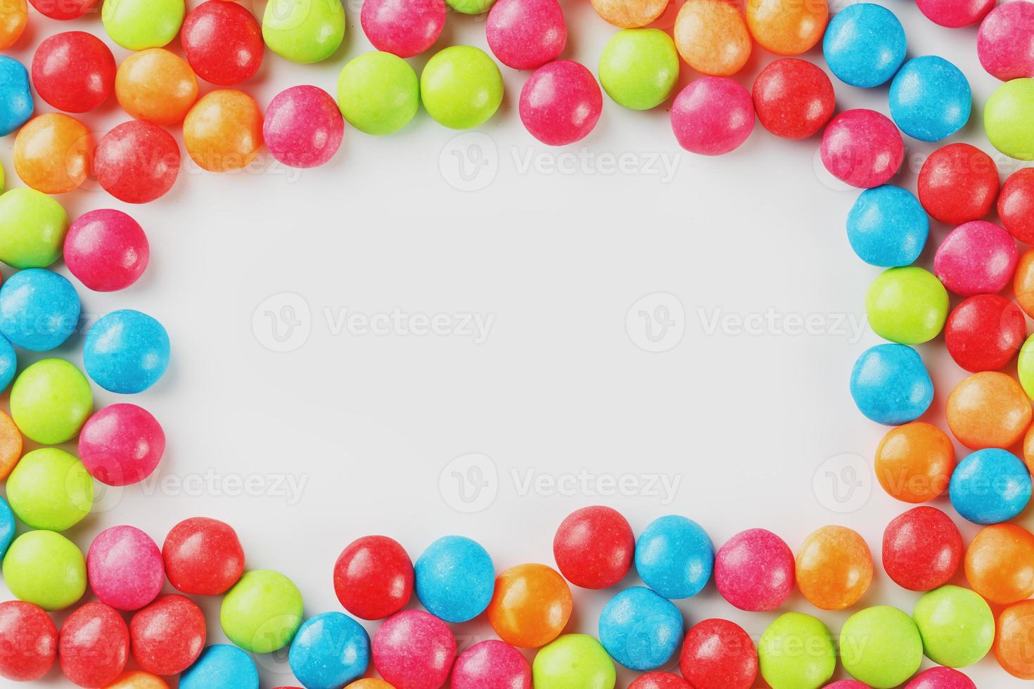 Frame of multi-colored candies close up. Rainbow colored dragee multicolored glaze on a white background photo