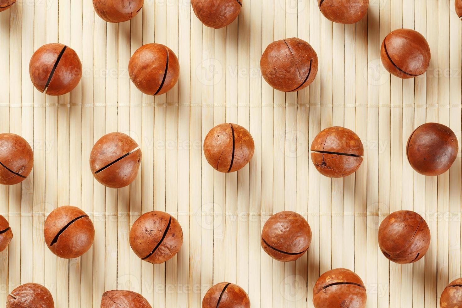 Flat composition with Australian macadamia nuts on bamboo light background. Patterns, repetitions photo