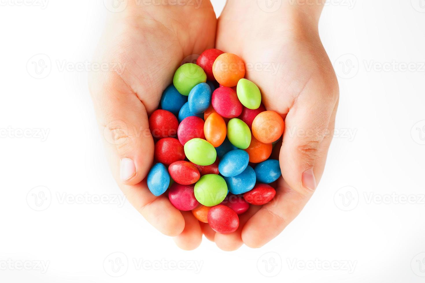Multicolored candies in the hands of a child on a white isolated background photo