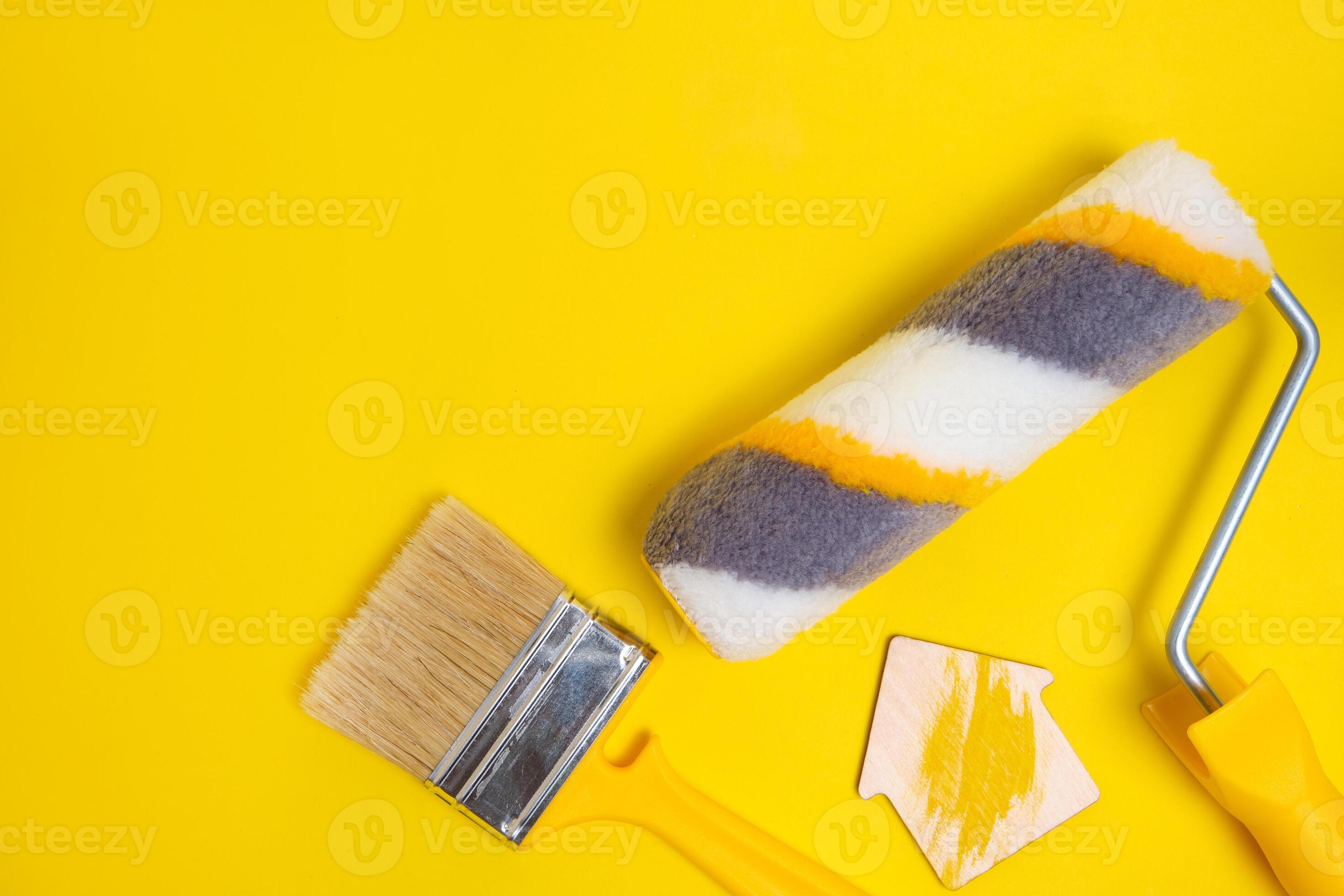 Paint roller, shield brush for painting walls on a yellow background