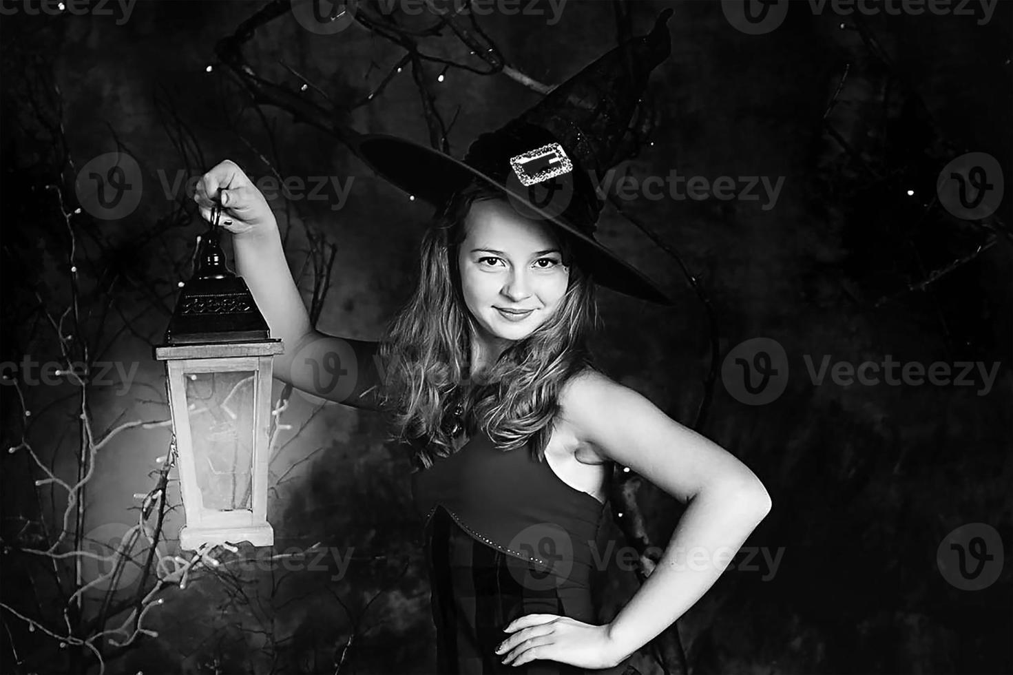 Halloween concept.A teenage girl in a witch costume and a lantern in her hands for Halloween. Black and white photo