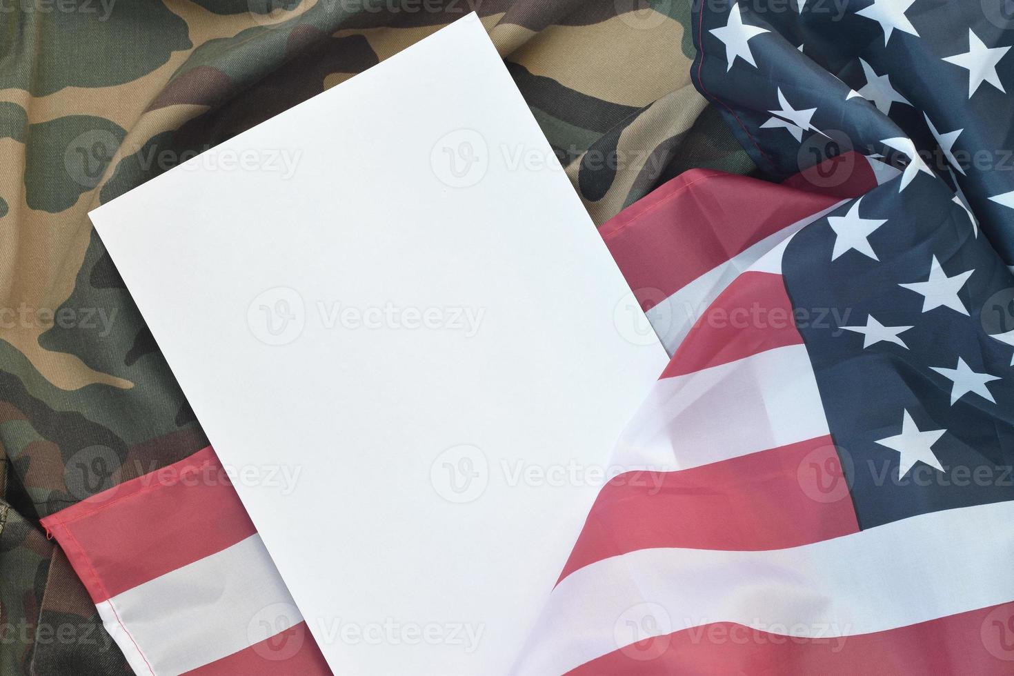 Blank paper lies on United States of America flag and folded military uniform jacket. Military symbols conceptual background banner and copy space photo
