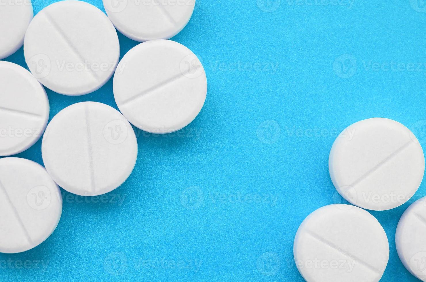 unas pocas tabletas blancas yacen sobre una superficie de fondo azul brillante. imagen de fondo sobre temas médicos y farmacéuticos foto