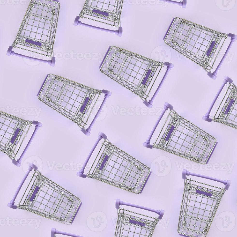 Pattern of many small shopping carts on a violet background. Minimalism flat lay top view photo