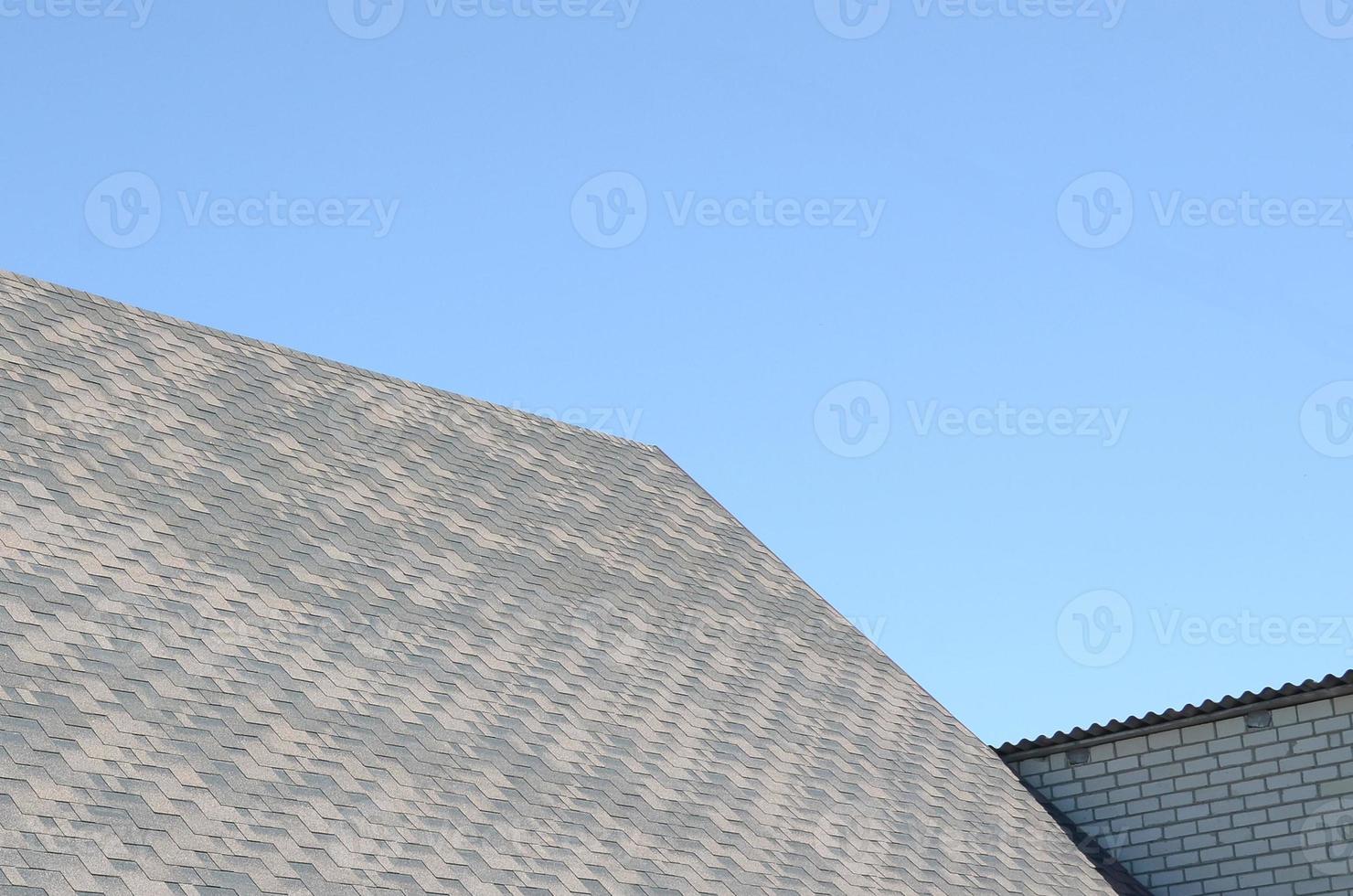 Flexible shingles of bitumen roofing surface on the brick house photo