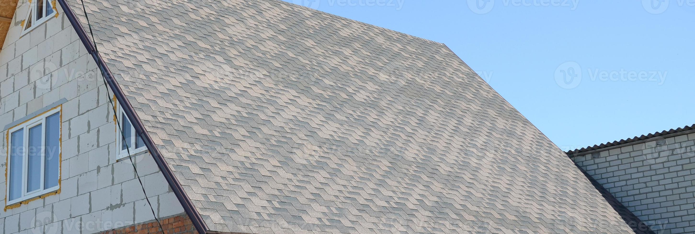 Flexible shingles of bitumen roofing surface on the brick house photo