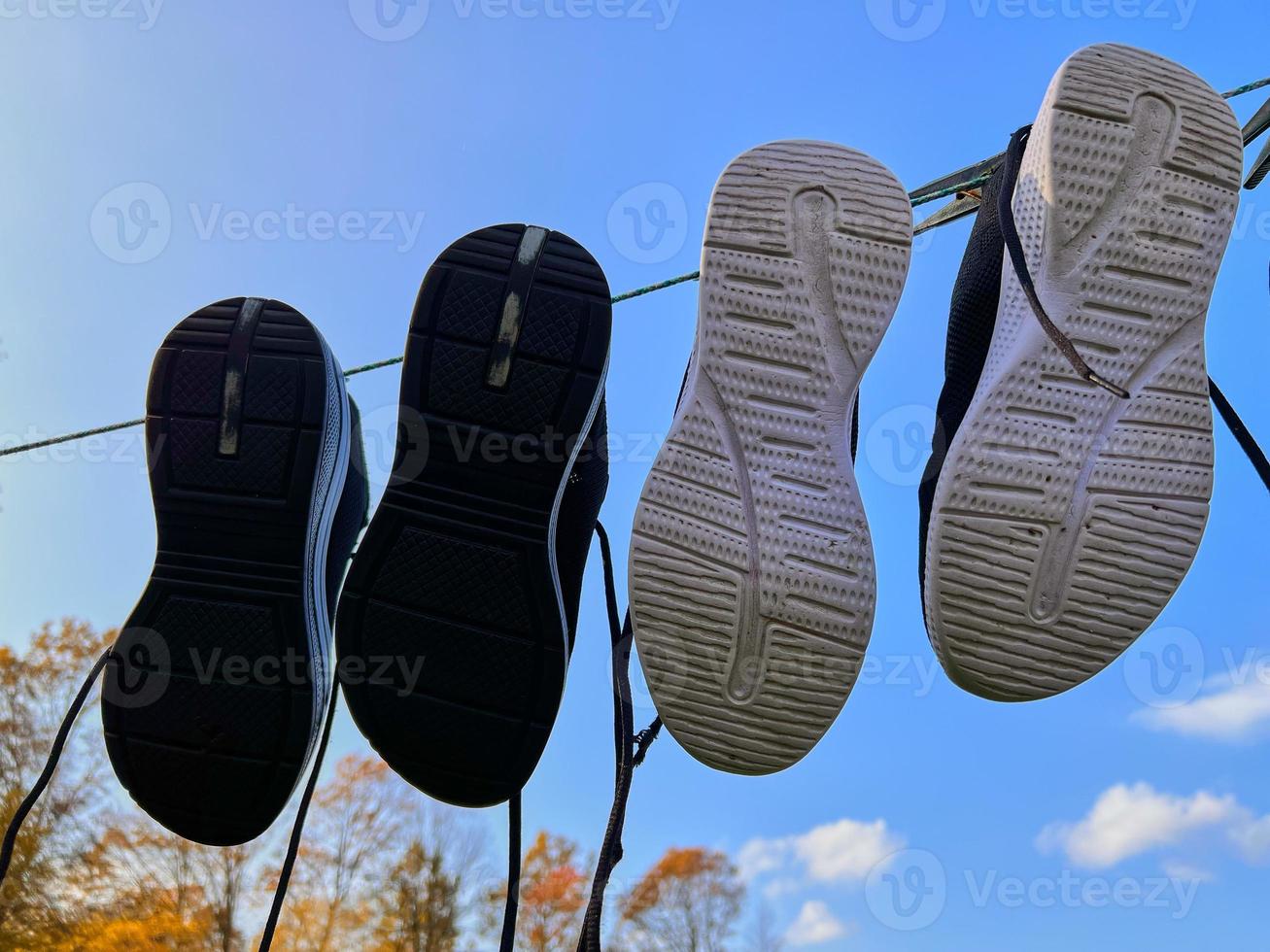 Two pairs of sneakers are drying on a clothesline against a blue sky. photo