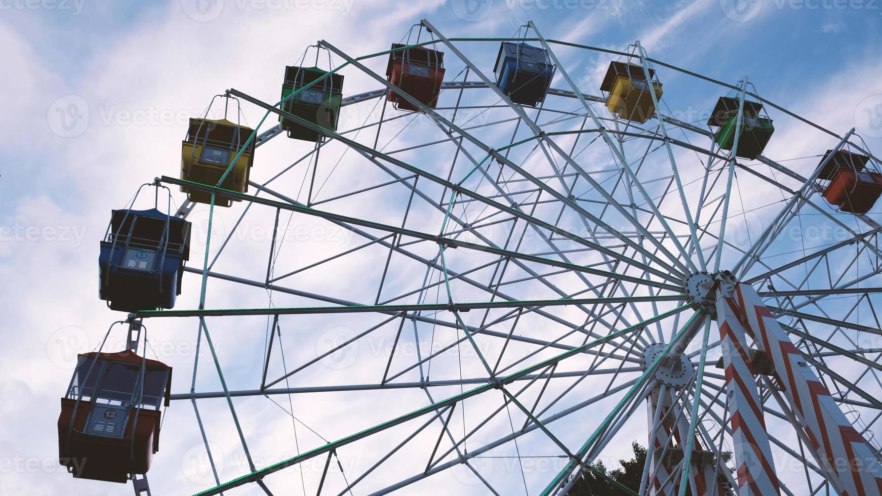 coloridas ruedas de ferris en el parque de atracciones sobre un fondo de cielo azul con nubes. imagen tonificada. vista inferior foto