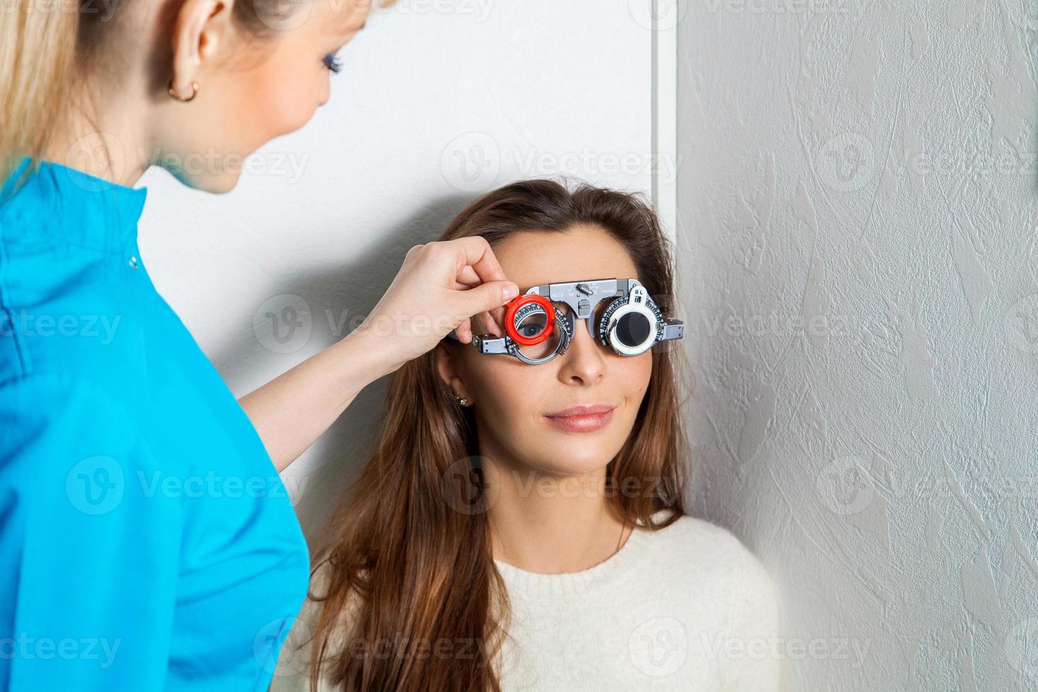 Adult woman checks vision in an ophthalmologist with corrective lenses photo