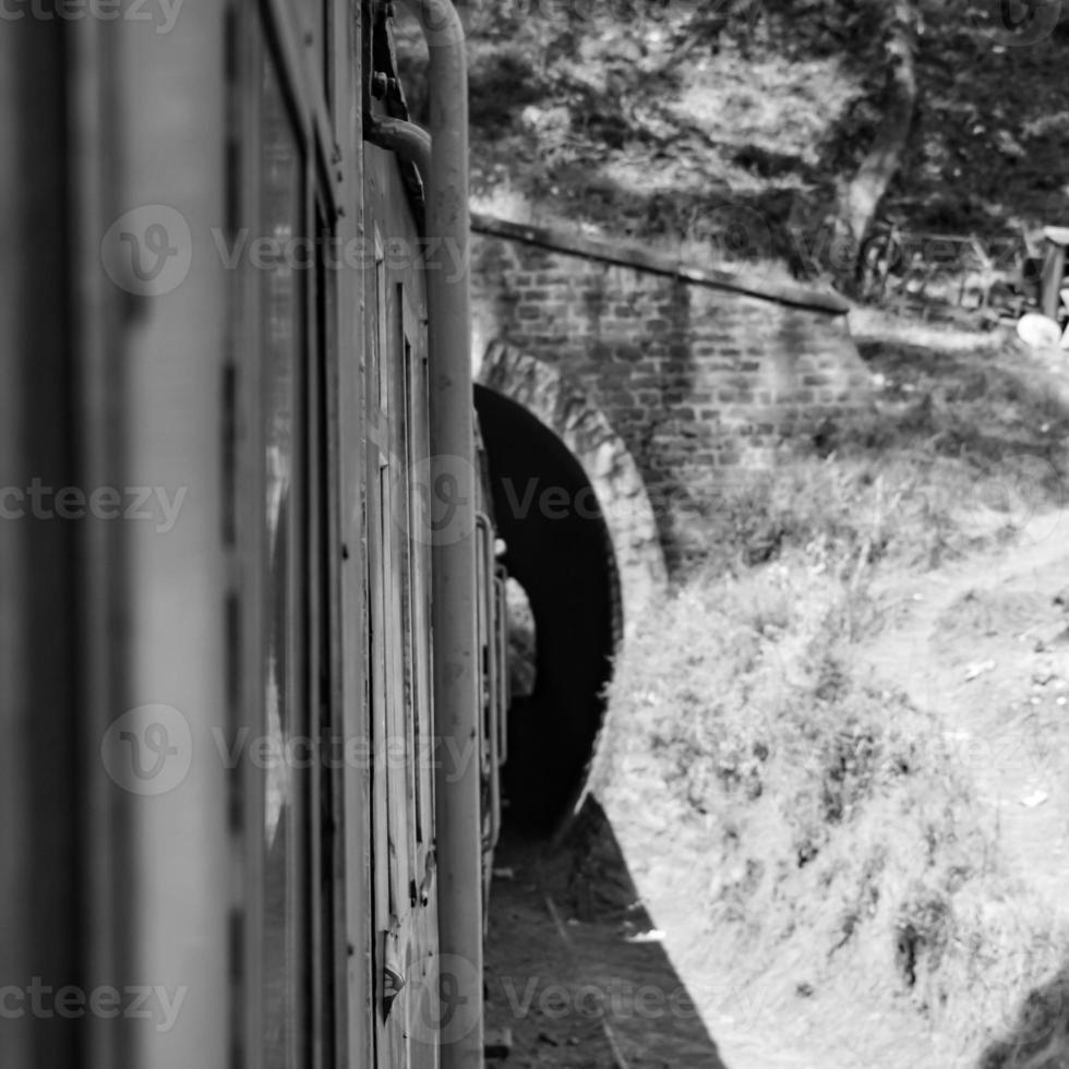 Toy Train moving on mountain slope, beautiful view, one side mountain, one side valley moving on railway to the hill, among green natural forest.Toy train from Kalka to Shimla in India-Black and White photo