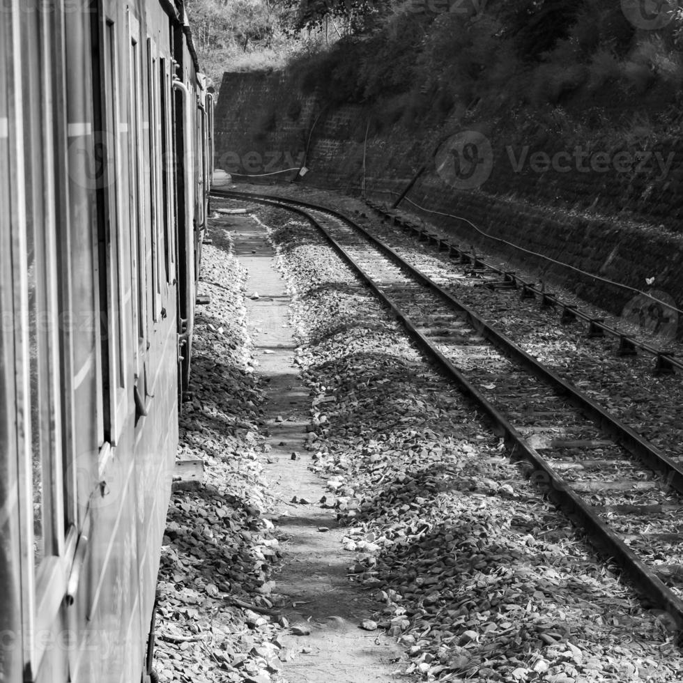 Toy Train moving on mountain slope, beautiful view, one side mountain, one side valley moving on railway to the hill, among green natural forest.Toy train from Kalka to Shimla in India-Black and White photo