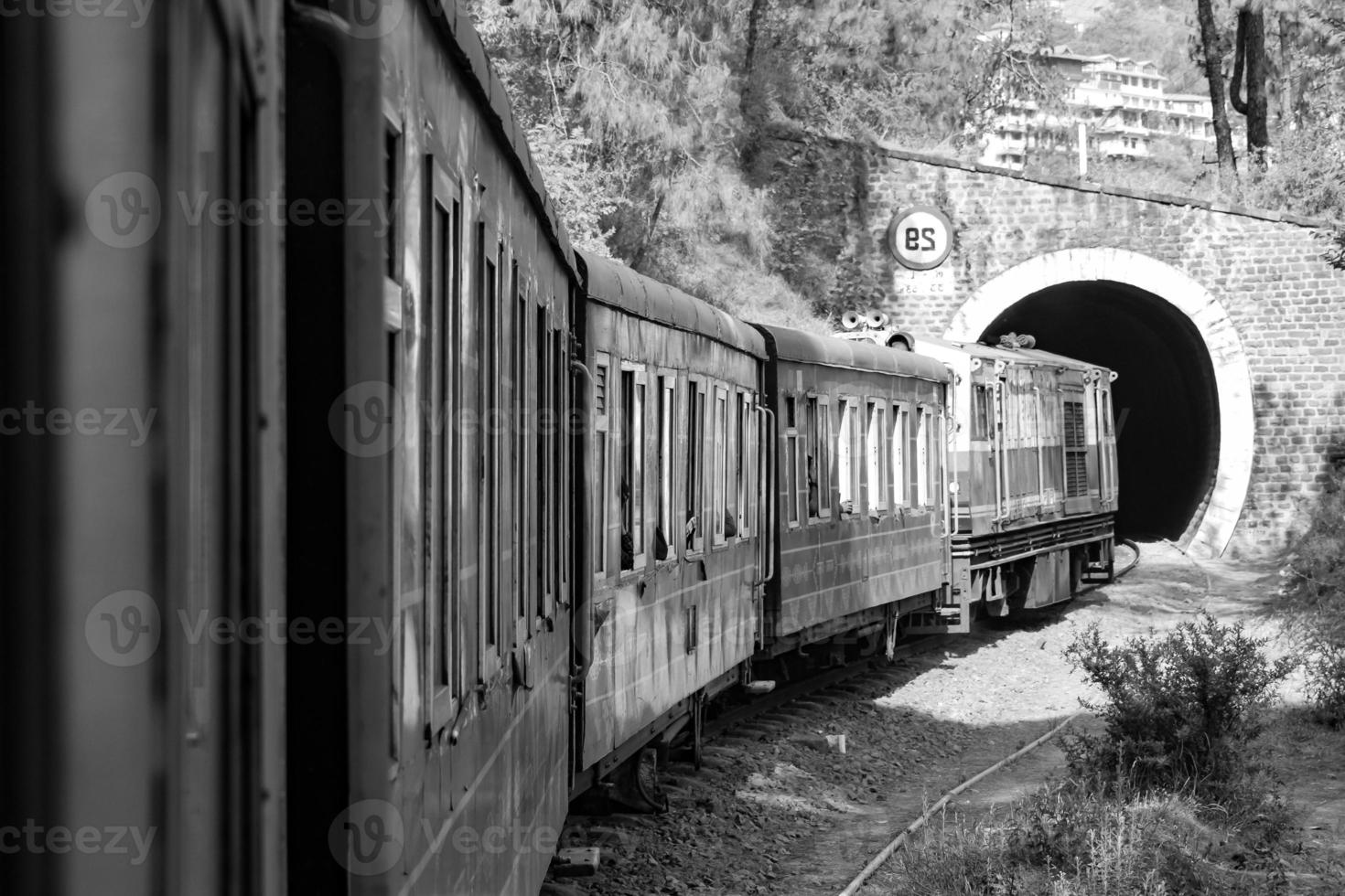 Toy Train moving on mountain slope, beautiful view, one side mountain, one side valley moving on railway to the hill, among green natural forest.Toy train from Kalka to Shimla in India-Black and White photo
