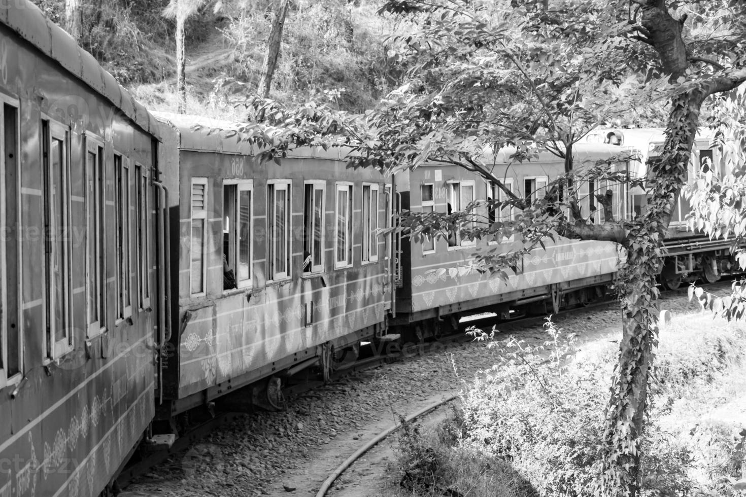 Toy Train moving on mountain slope, beautiful view, one side mountain, one side valley moving on railway to the hill, among green natural forest.Toy train from Kalka to Shimla in India-Black and White photo