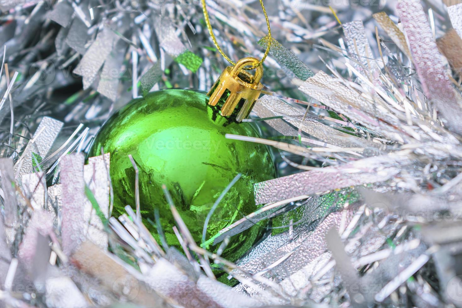 una bola de navidad verde y brillante se encuentra entre el oropel de año nuevo foto