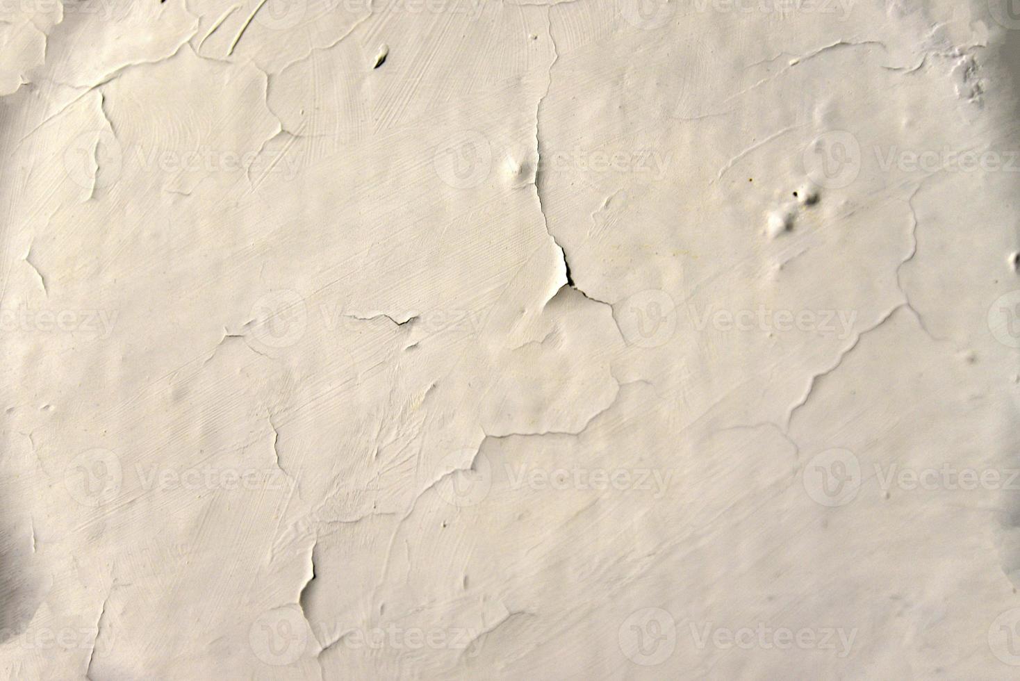 A whitewashed wall in the bathroom with cracks from water drips. Wall and falling off paint with cracks. The old wall. photo