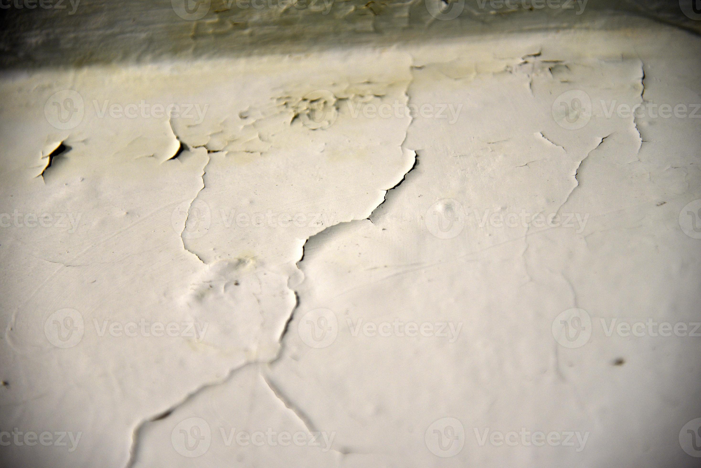 A whitewashed wall in the bathroom with cracks from water drips. Wall