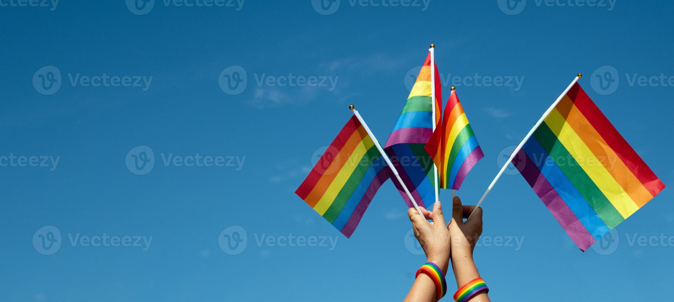 Look up view of rainbow flag, LGBT simbol, against clear bluesky background, soft and  selective focus, concept for LGBT celebration in pride month, June, around the world, copy space. photo