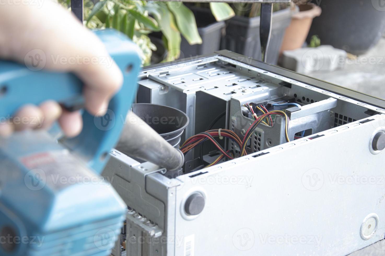 Cleaning a dusty computer with a blower. photo