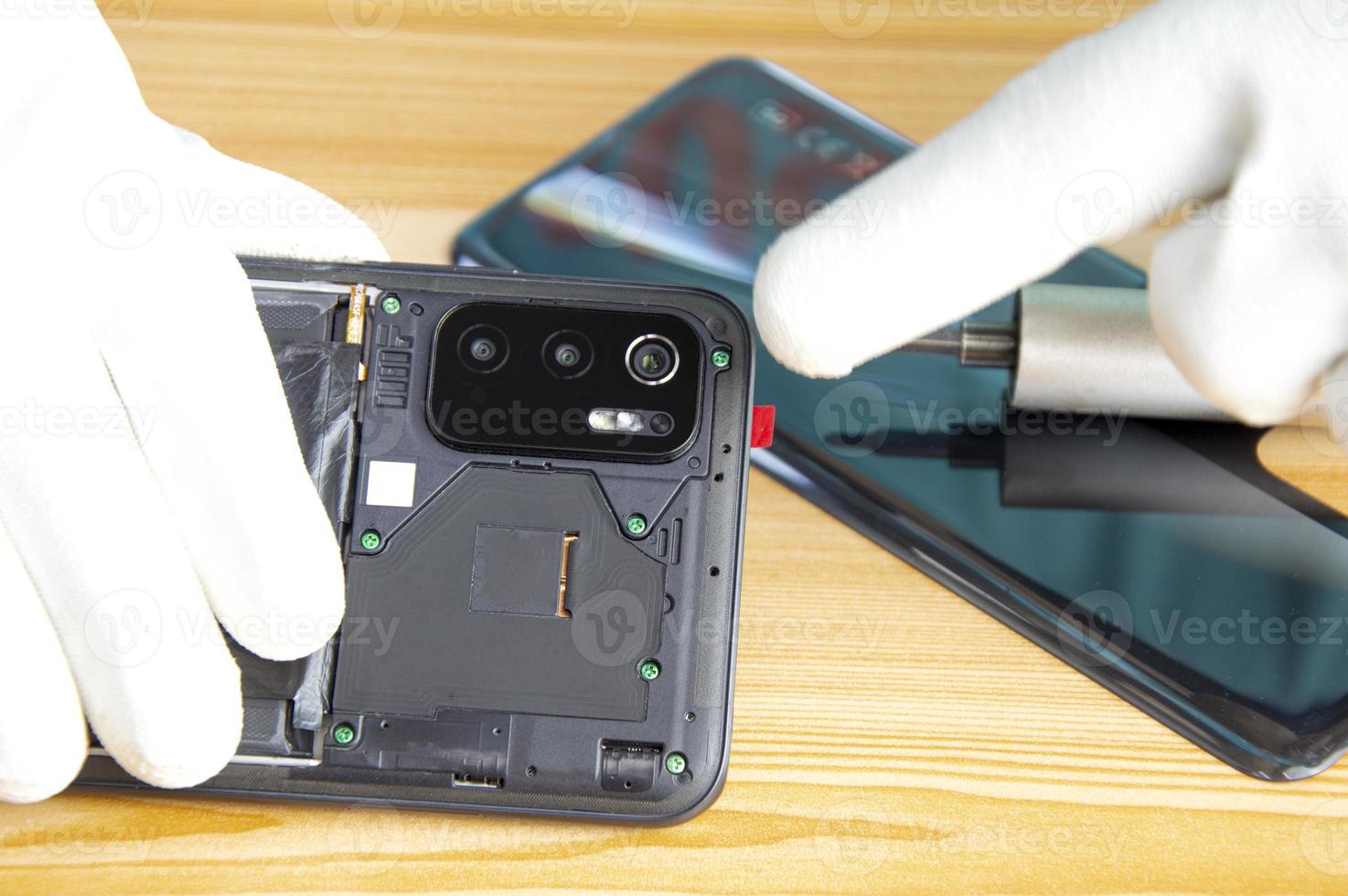 Image of a technician screwing the back of a mobile phone photo