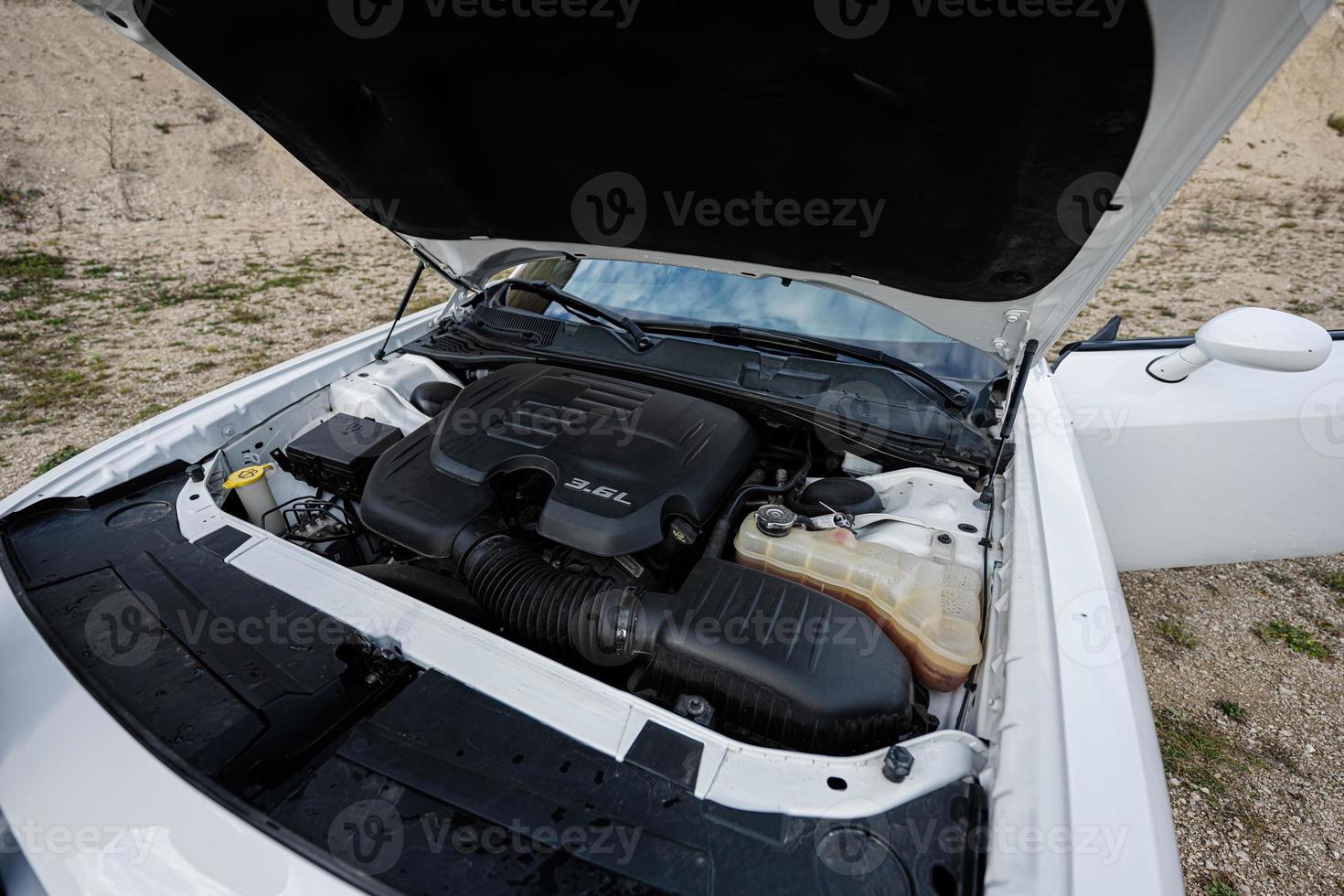 Open hood of white muscle car, engine. photo