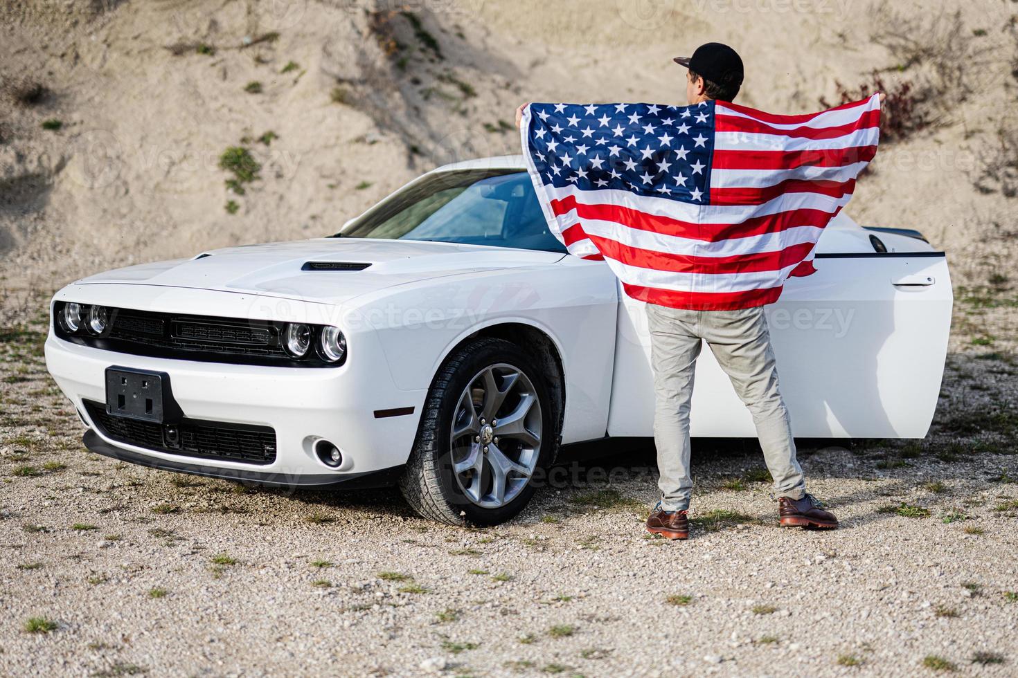 Back of man with USA flag near his white american muscle car in career. photo