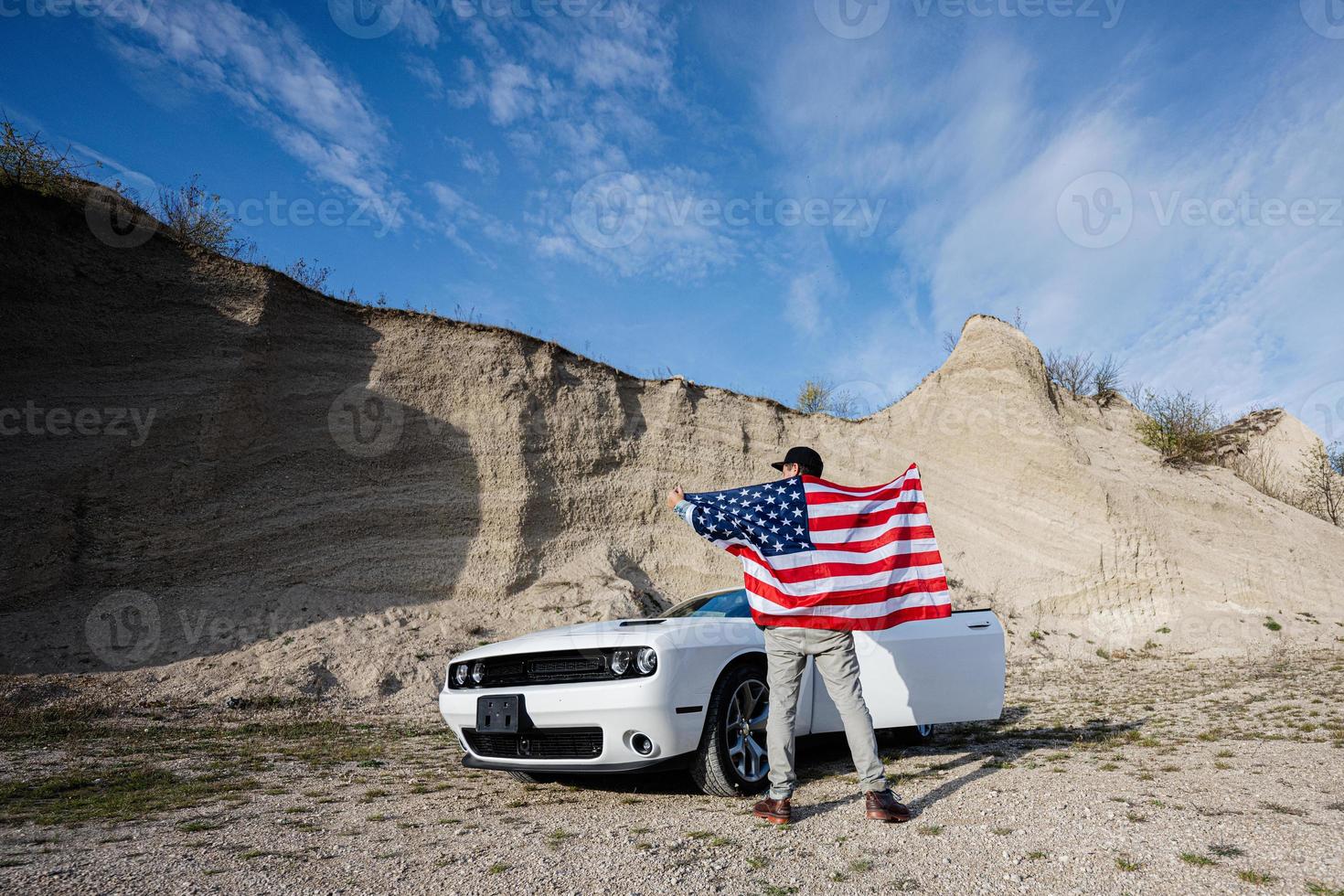 Back of man with USA flag near his white american muscle car in career. photo