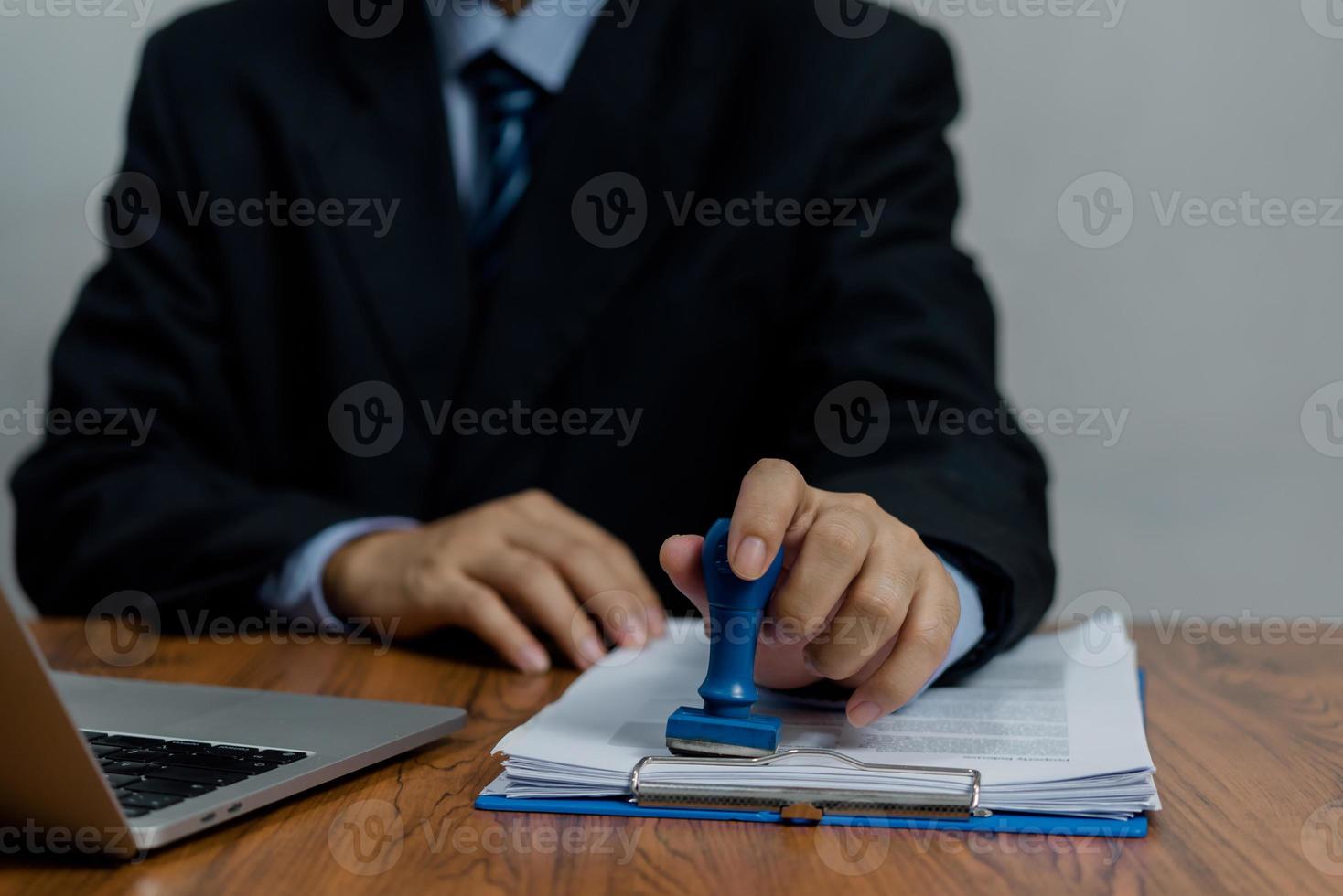 hombre que sella la aprobación de la banca de financiación del trabajo o los documentos de marketing de inversión en el escritorio. foto