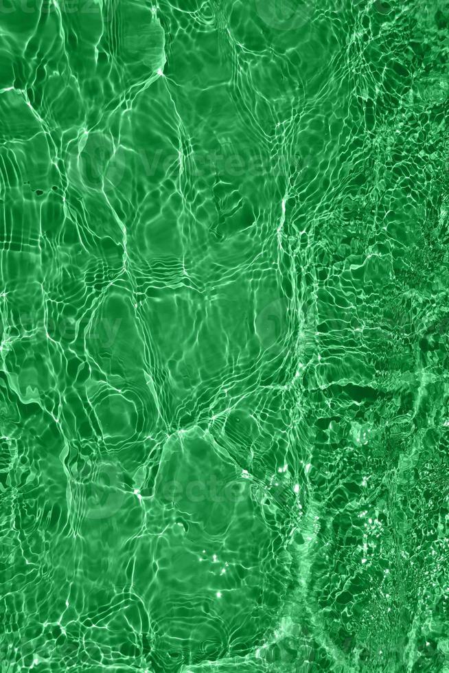Defocus blurred transparent green colored clear calm water surface texture with splashes and bubbles. Trendy abstract nature background. Water waves in sunlight with copy space. Green watercolor shine photo