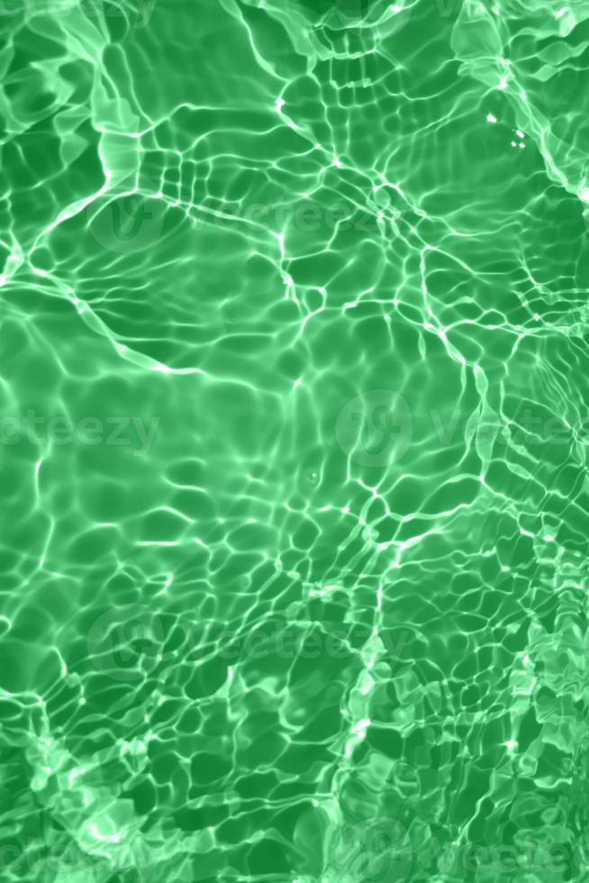 Defocus blurred transparent green colored clear calm water surface texture with splashes and bubbles. Trendy abstract nature background. Water waves in sunlight with copy space. Green watercolor shine photo