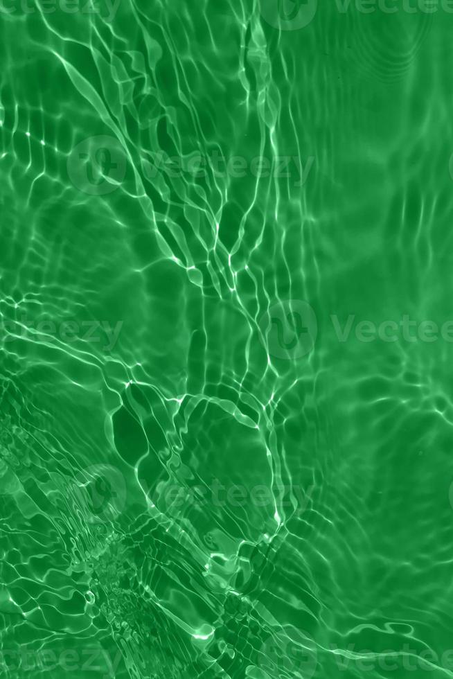Defocus blurred transparent green colored clear calm water surface texture with splashes and bubbles. Trendy abstract nature background. Water waves in sunlight with copy space. Green watercolor shine photo