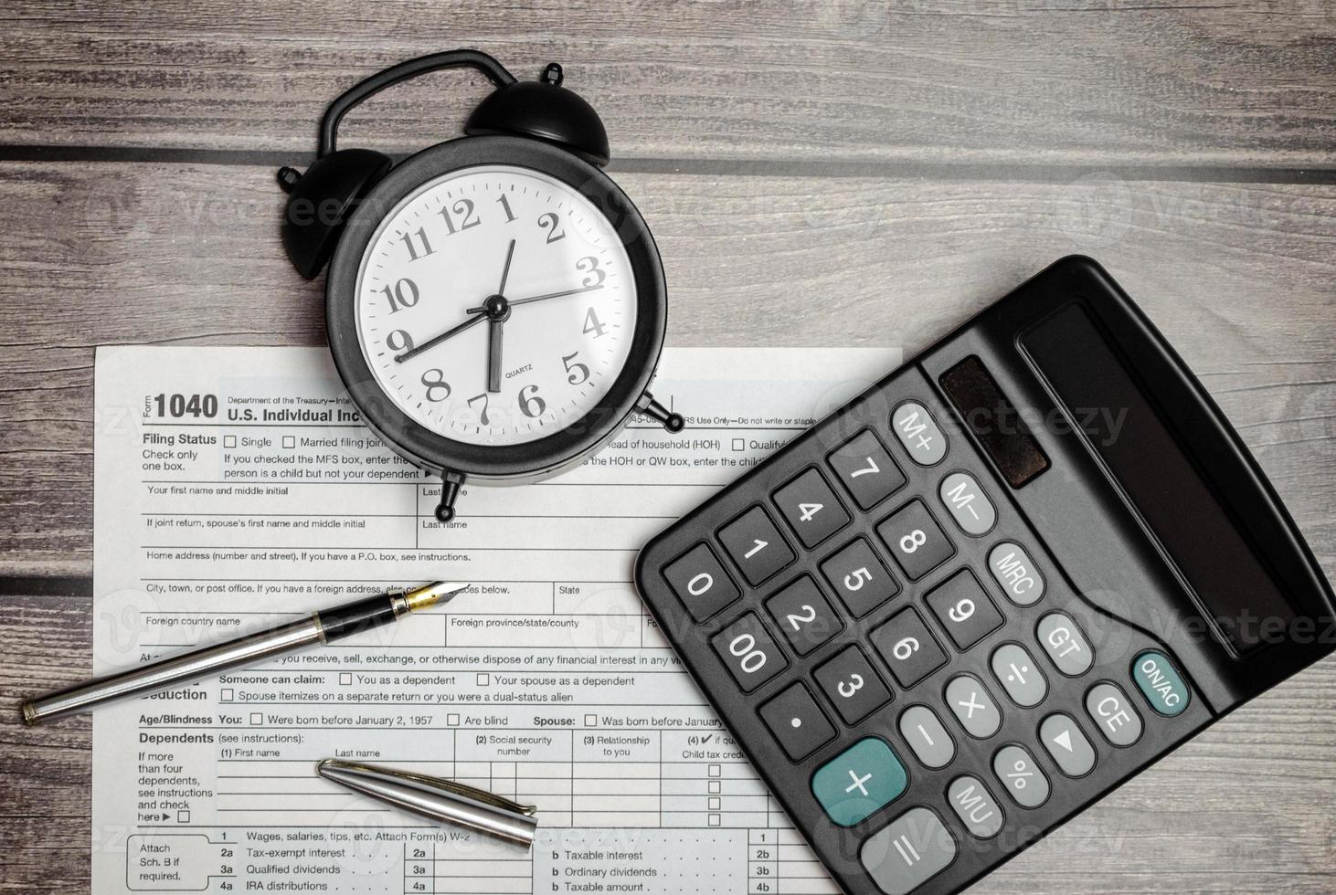 Top view tax form 1040 with pen, calculator and black alarm clock. tax time. financial document. photo