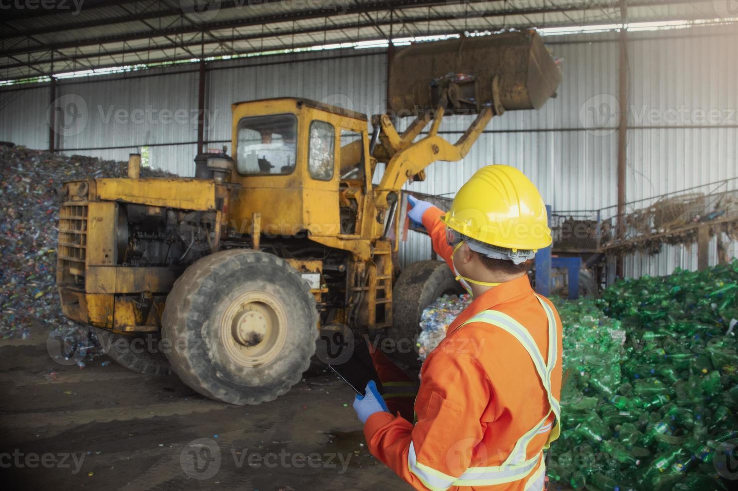 engineer worker in protective uniform and with hardhat using tablet for checking working. recycling industry. photo