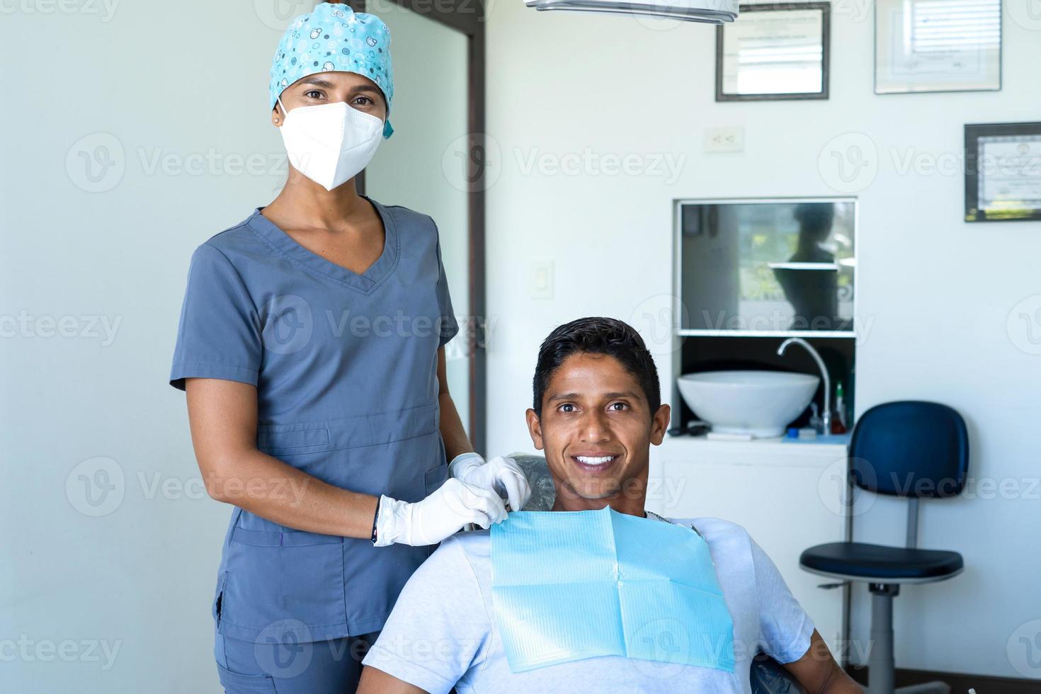 retrato de paciente masculino feliz y dentista bastante joven. foto