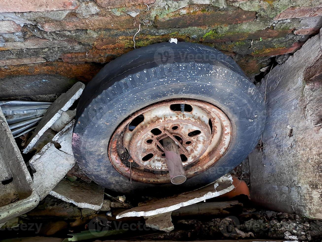 old car rims, flat and cracked, rusted through the brick wall. photo