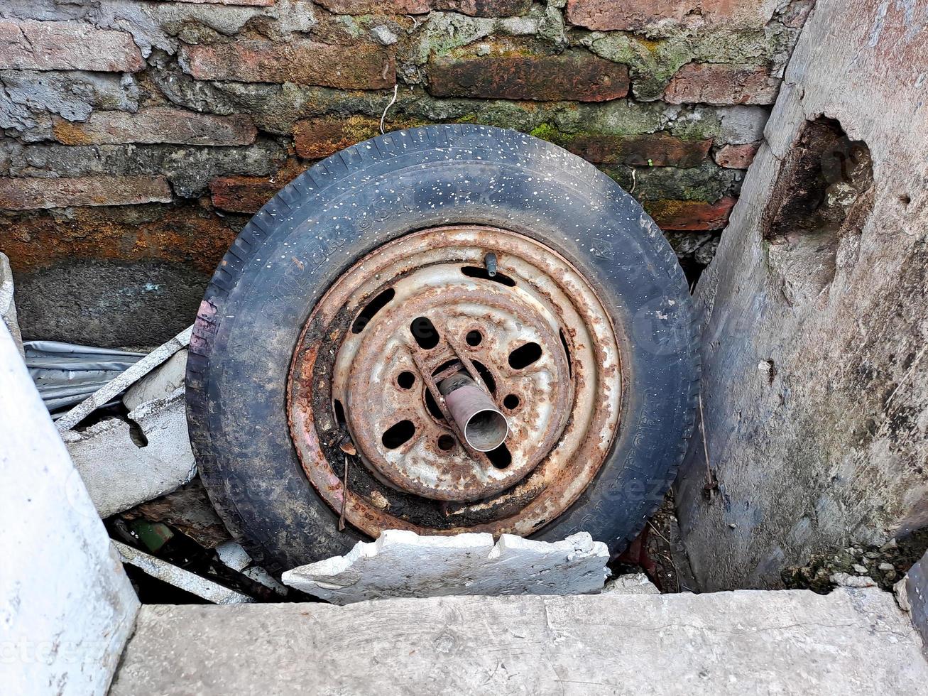 old car rims, flat and cracked, rusted through the brick wall. photo