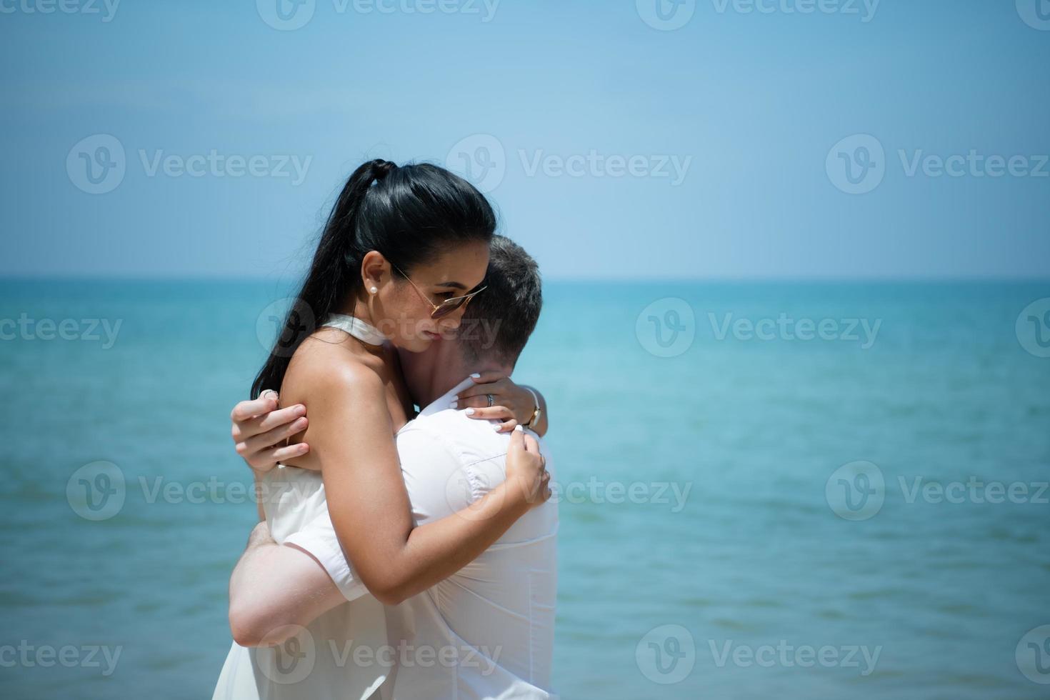 A young white man Asking for an Asian girl to marry with a diamond ring on a beach photo