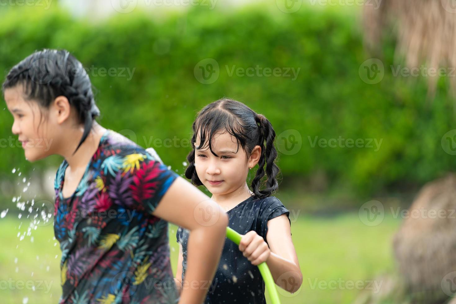 niños lavando el lodo después de divertirse jugando toboganes de lodo en los campos comunitarios. foto