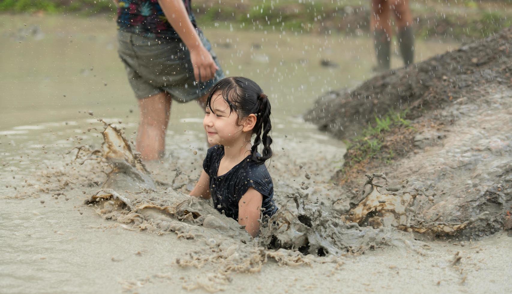 Little girls have fun playing in the mud in the community fields photo