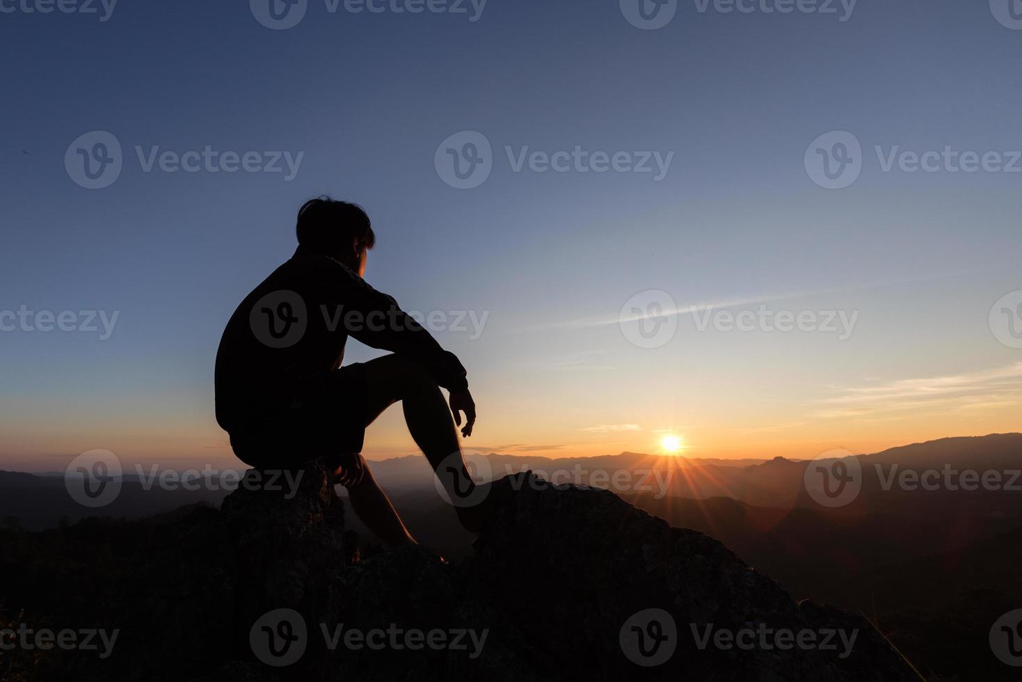 silueta de hombre triste sentado solo en la cima de una montaña al atardecer, depresión y soledad. el concepto de estrés y tristeza. foto