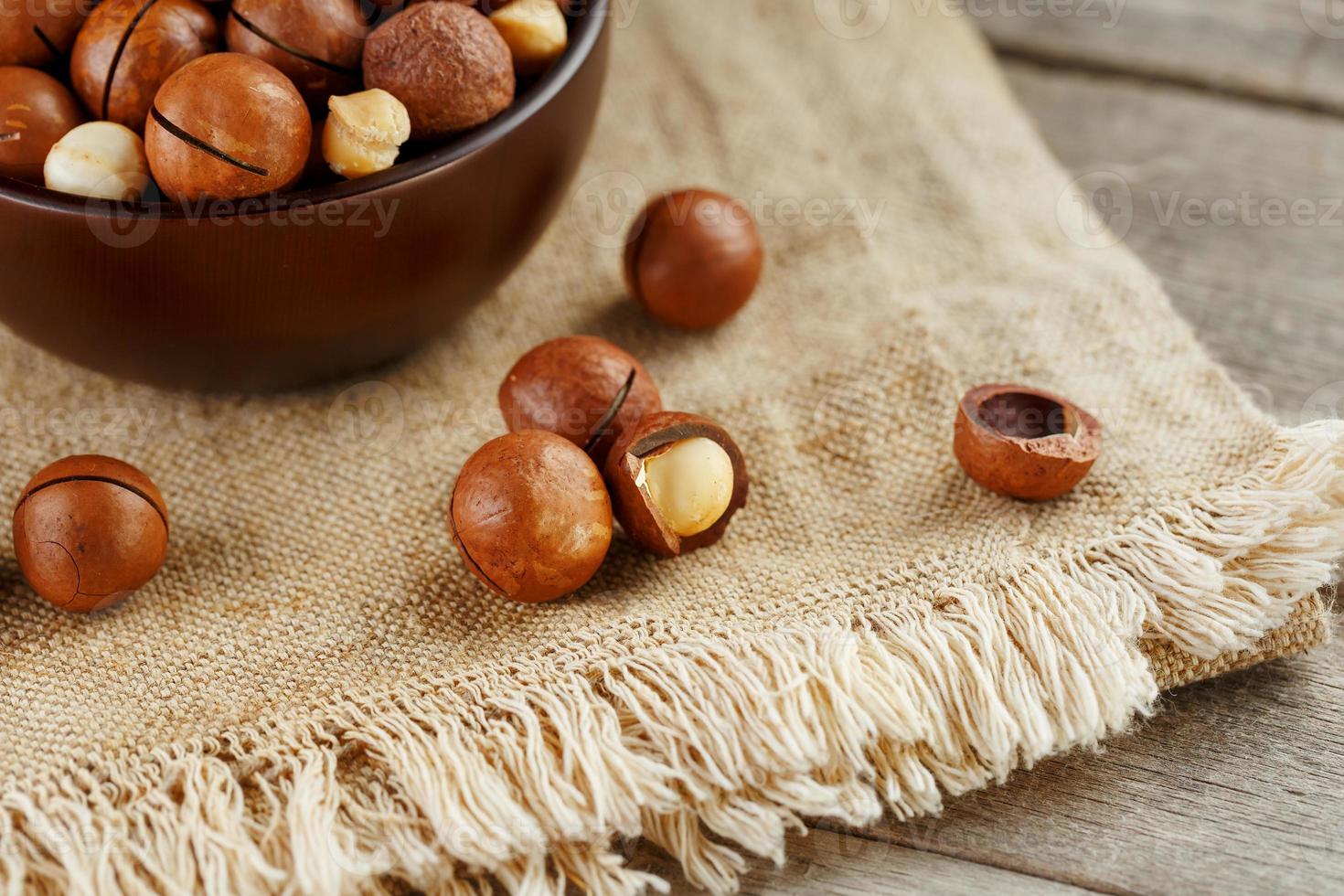 nuez de macadamia sobre fondo de madera con tela vintage, concepto de superalimentos y alimentos saludables foto