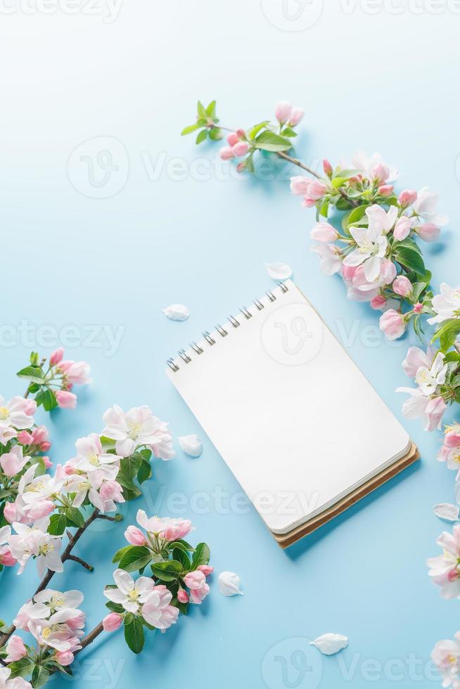 Blooming spring sakura on a blue background with notepad space for a greeting message. The concept of spring and mother's day. Beautiful delicate pink cherry flowers in springtime photo