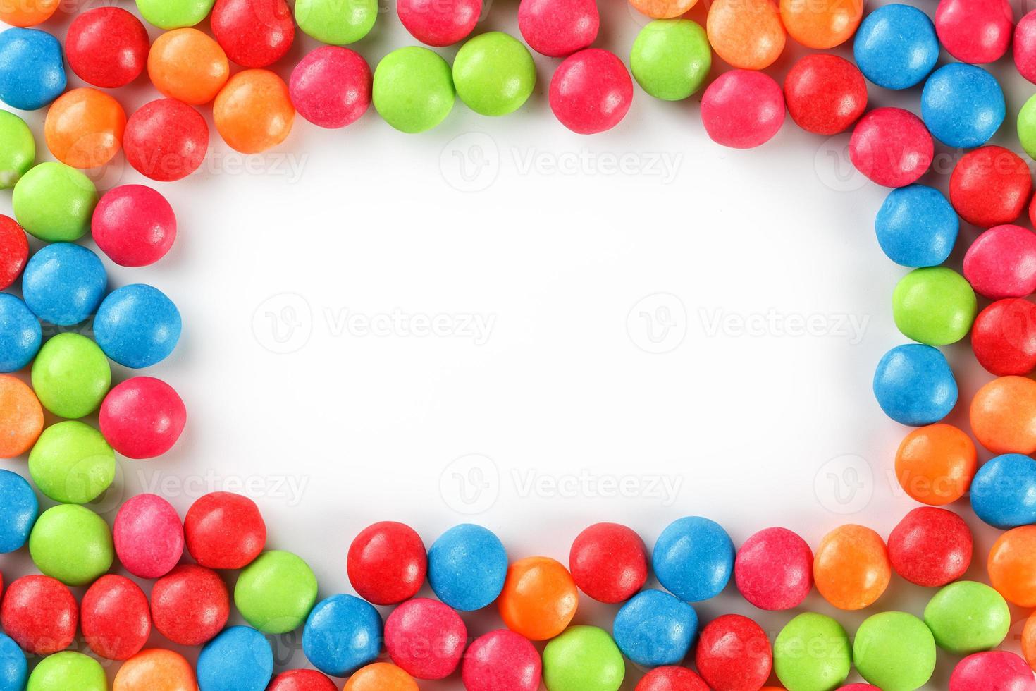 Frame of multi-colored candies close up. Rainbow colored dragee multicolored glaze on a white background photo