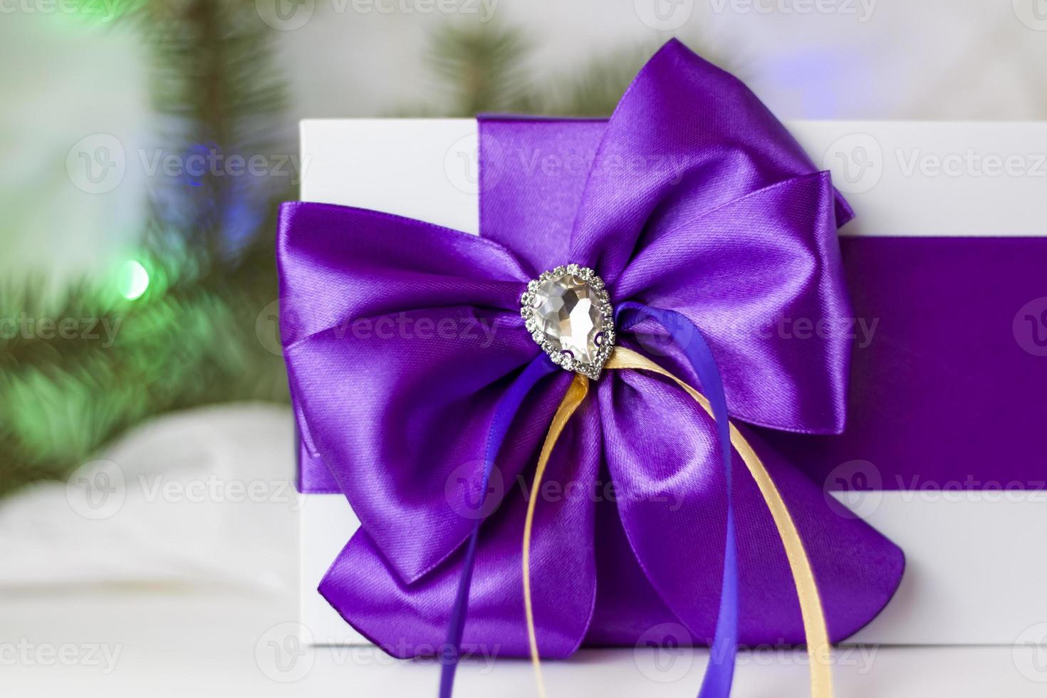 A Christmas gift decorated with a beautiful bow on a light background with a fir twig. Gifts, joy, surprise. Selective focus. the concept of Christmas and New Year. photo