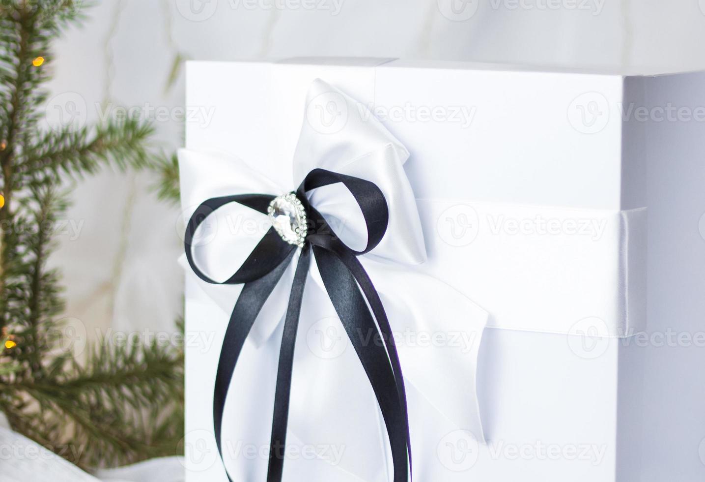 A Christmas gift decorated with a beautiful bow on a light background with a fir twig. Gifts, joy, surprise. Selective focus. the concept of Christmas and New Year photo