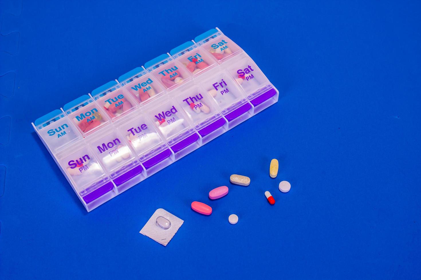 Weekly Pills In Pill Box On Smooth Blue Background photo